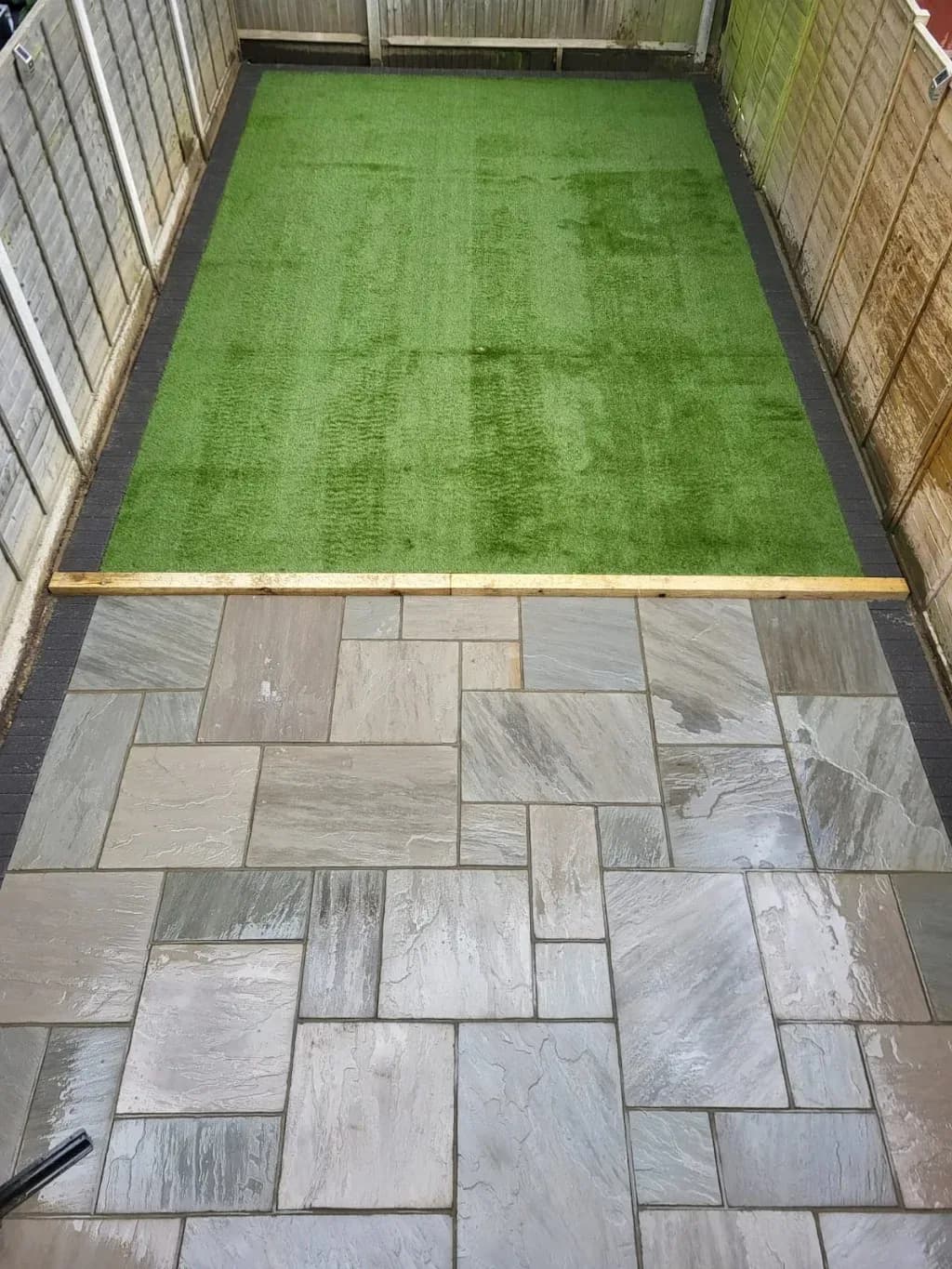 Artificial lawn strip alongside a sandstone patio
