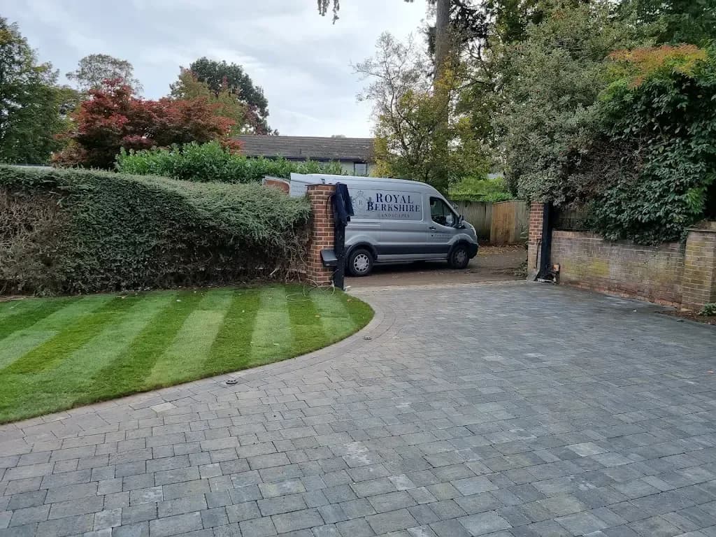 Block paved driveway curving past a neat striped lawn