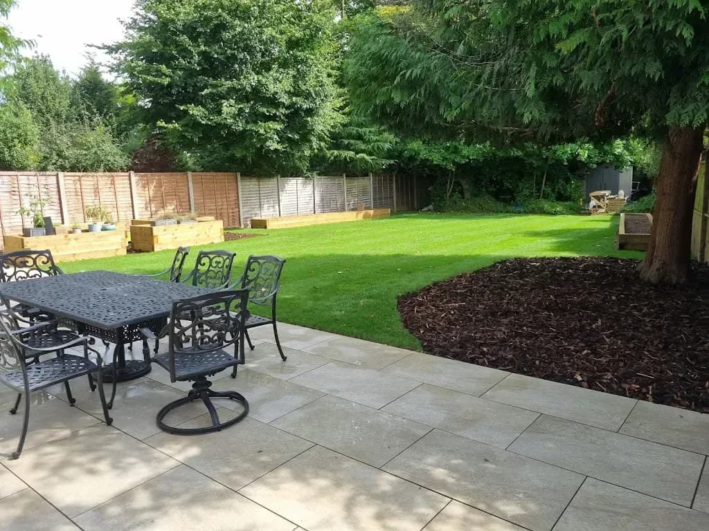 Sandstone patio with a dining set overlooking a lawn