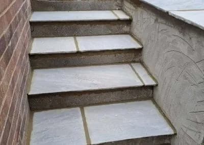 Sandstone steps beside a rendered retaining wall
