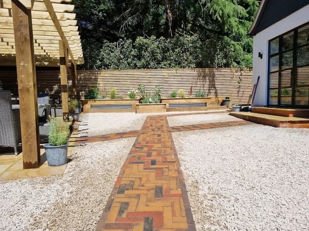 Timber pergola beside a gravel garden with a brick paver path