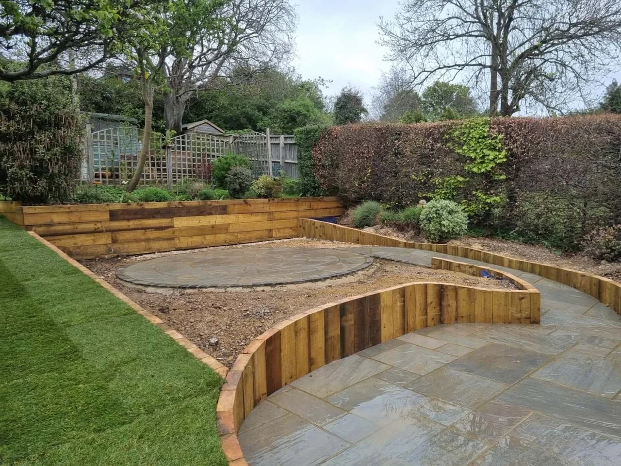 Curved sleeper edged raised patio with newly laid turf